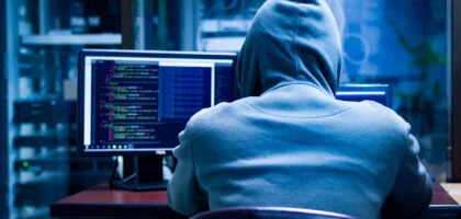 a person in a hoodie looking at a computer screen