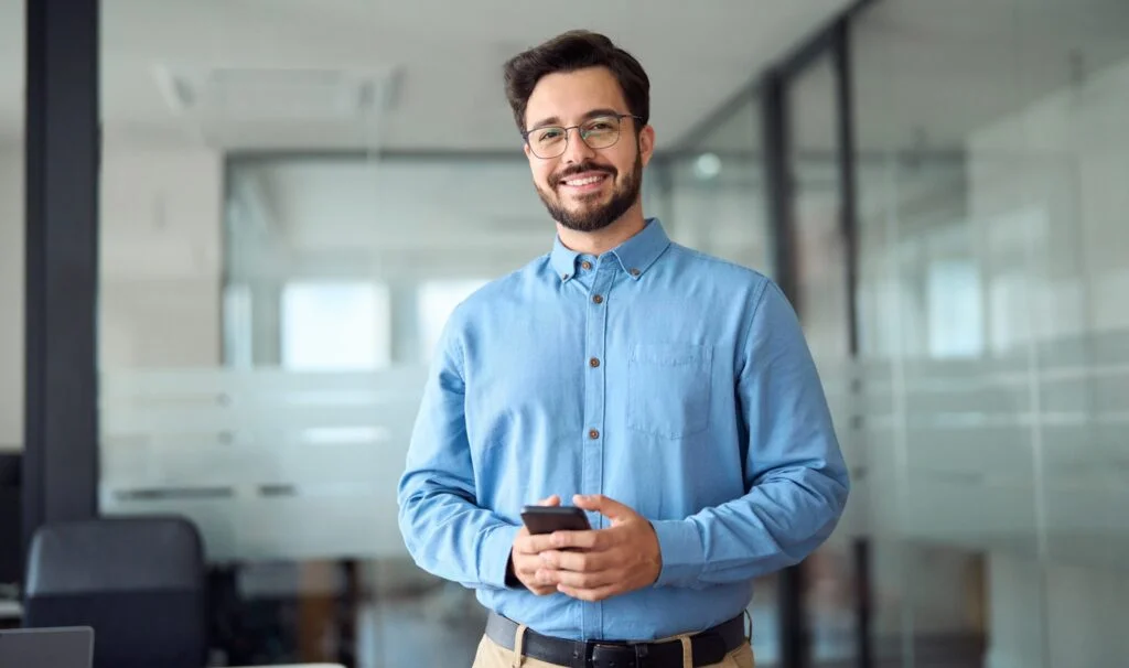 a man smiling while holding a phone